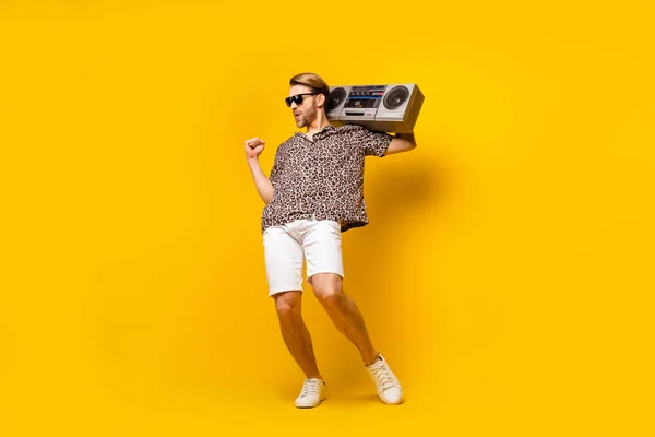 Lunghezza completa foto di fortunato funky giovane ragazzo indossare leopardo vestito scuro occhiali danza boom box alzando pugno isolato colore giallo sfondo — Foto Stock