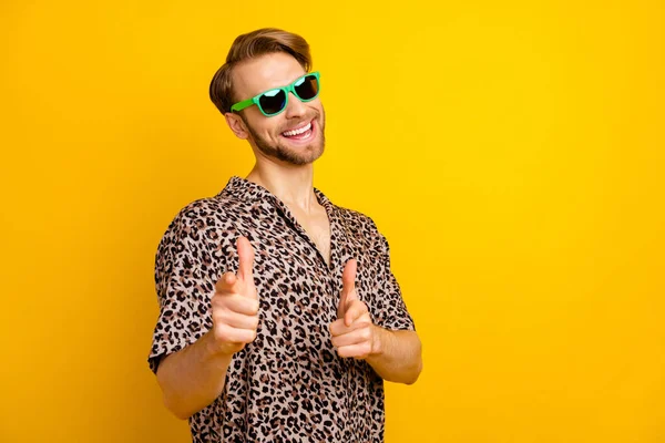 Çekici bir genç adamın fotoğrafı leopar desenli elbiseler giyiyor koyu renk gözlük parmağıyla işaret ediyor sarı arka plan. — Stok fotoğraf