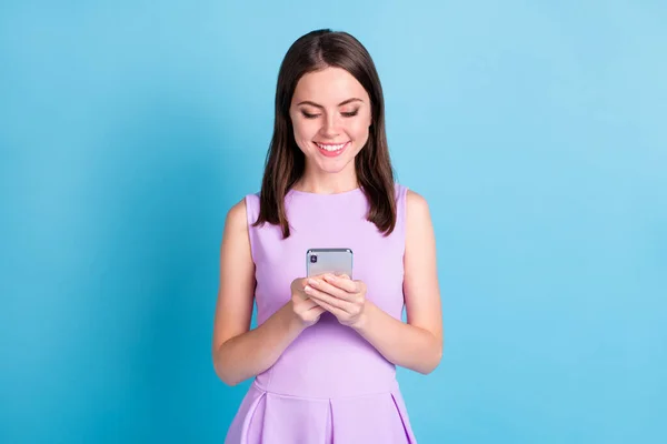 Fotografie šťastné pozitivní mladá žena držet vzhled telefonu závislý uživatel chatování izolované na modrém pozadí — Stock fotografie