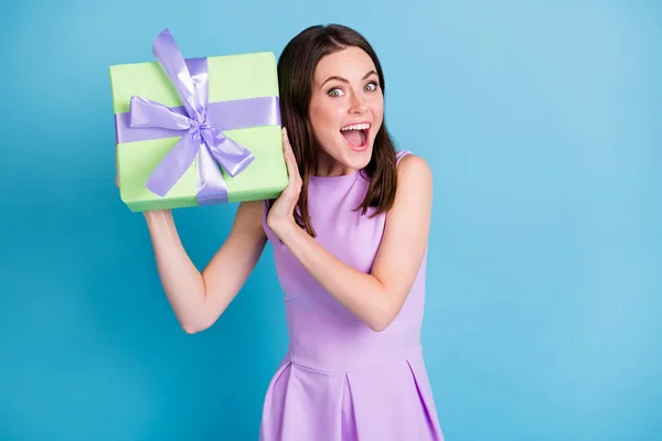 Foto de feliz encantadora mujer joven agitar presente esperar sorpresa buen humor celebrar caja de regalo aislado en fondo de color azul —  Fotos de Stock