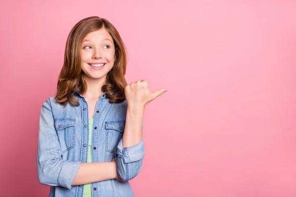 Foto retrato menina sorrindo mostrando polegar espaço em branco curioso interessado isolado pastel cor de rosa fundo — Fotografia de Stock