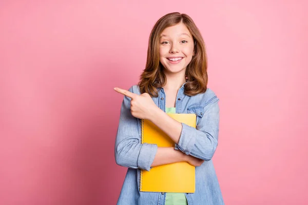 Foto de menina feliz sorriso positivo ponto dedo vazio espaço anúncio escolha segure notebook isolado sobre fundo cor pastel — Fotografia de Stock