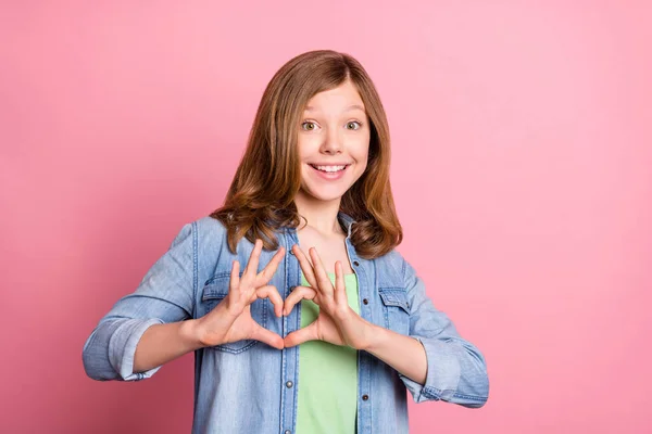 Foto retrato menina sorrindo mostrando sinal de coração com dedos sonhador feliz isolado pastel cor de fundo — Fotografia de Stock