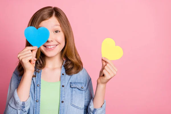 Foto retrato menina sorrindo escondendo olho atrás de papel coração isolado pastel cor rosa fundo — Fotografia de Stock