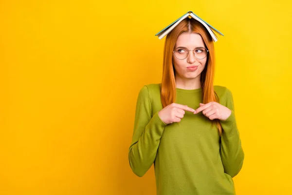 Foto der schüchternen roten Frisur junge Dame Buch auf dem Kopf sehen leeren Raum tragen grünen Pullover Brille isoliert auf gelbem Hintergrund — Stockfoto