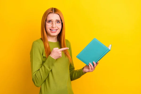 Foto van onder de indruk gember kapsel millennial dame punt boek dragen groene trui bril geïsoleerd op gele kleur achtergrond — Stockfoto