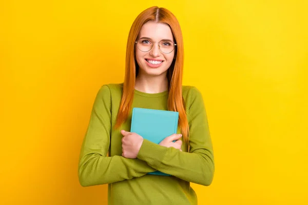 Foto der intelligenten roten Frisur junge Dame Umarmung Buch tragen grünen Pullover Brille isoliert auf gelbem Hintergrund — Stockfoto