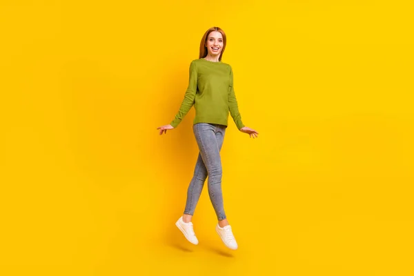 Pełne zdjęcie ciała pod wrażeniem pomarańczowe włosy młoda dama skakać nosić zielony sweter dżinsy izolowane na żółtym tle — Zdjęcie stockowe