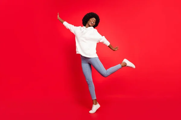 Plná velikost fotografie krásné vlnité účes dáma tanec nosit bílé sportovní oblečení džíny izolované na červeném pozadí — Stock fotografie