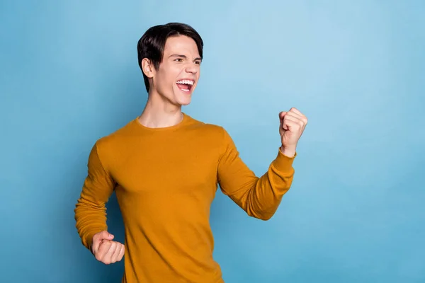Foto van hooray schreeuwen brunet millennial guy handen vuisten dragen bruine trui geïsoleerd op blauwe kleur achtergrond — Stockfoto