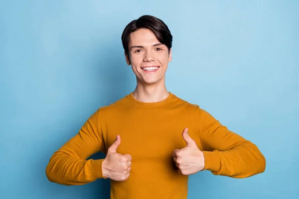 Zdjęcie śmieszne brunet młody facet pokazać kciuk do góry nosić brązowy sweter izolowane na tle niebieskiego koloru — Zdjęcie stockowe