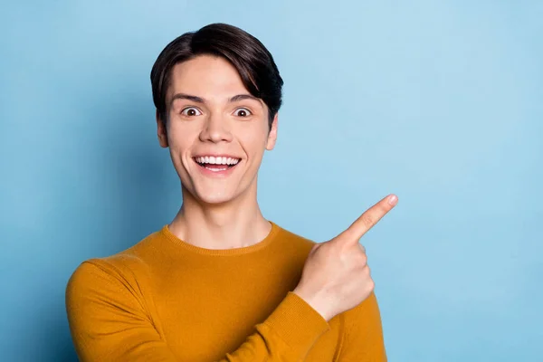 Foto von beeindruckt Brunet Millennial Kerl Punkt leeren Raum tragen braunen Pullover isoliert auf blauem Hintergrund — Stockfoto