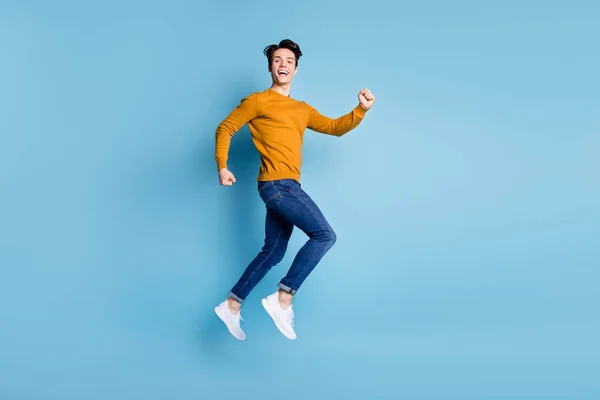 Foto de perfil de cuerpo completo de la morena impresionada millennial chico salto desgaste pantalones vaqueros aislados en fondo de color azul —  Fotos de Stock