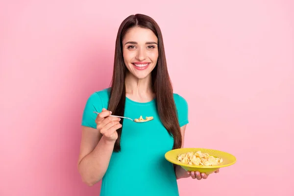 Foto de mujer joven feliz sonrisa positiva comer copos de maíz comida saludable desayuno aislado sobre fondo de color rosa —  Fotos de Stock