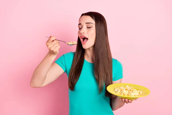 Foto del lado del perfil de la mujer joven comer cereales dieta comida cuchara plato nutrición aislado sobre fondo de color rosa —  Fotos de Stock