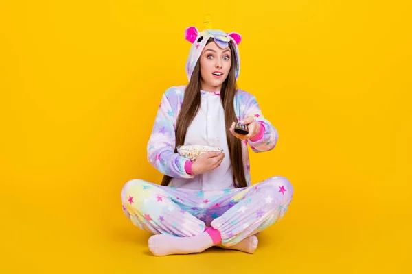 Retrato de menina alegre na moda atraente vestindo roupas engraçadas assistindo série comendo milho isolado sobre fundo de cor amarela brilhante — Fotografia de Stock