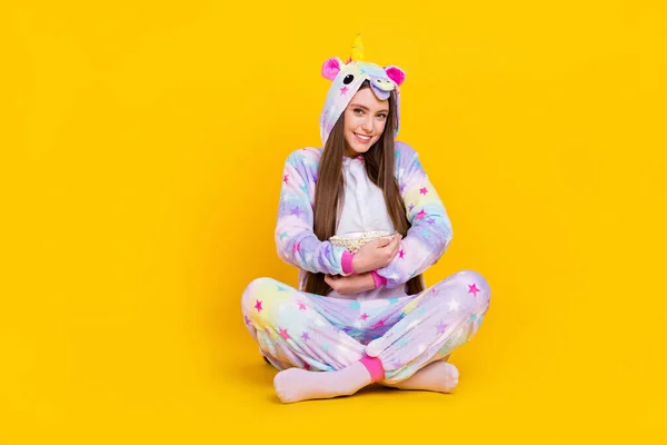 Retrato de menina alegre atraente sentado postura de lótus comer abraçando milho passar tempo livre isolado sobre fundo de cor amarelo brilhante — Fotografia de Stock