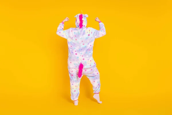 Full längd kropp storlek foto tillbaka visa barnslig flicka bär pyjamas visar styrka isolerad ljus gul färg bakgrund — Stockfoto