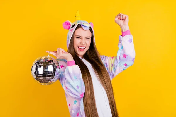 Retrato de menina sortuda alegre atraente vestindo kingurumi segurando bola se divertindo isolado sobre fundo de cor amarela brilhante — Fotografia de Stock