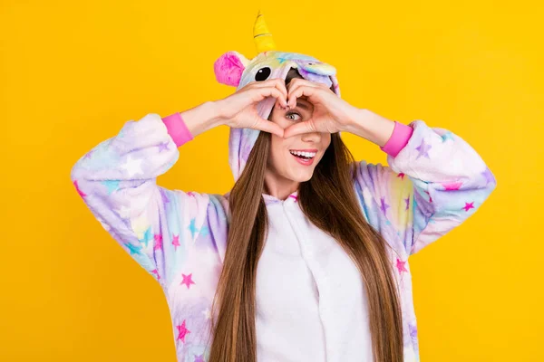 Foto retrato mujer adolescente divertido pijama buscando mostrando corazón signo dedos aislado vibrante amarillo fondo —  Fotos de Stock