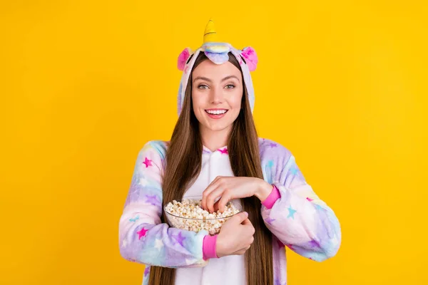 Foto de alegre jovem menina feliz segurar as mãos tigela pop corn smile nightwear isolado no fundo de cor amarela — Fotografia de Stock
