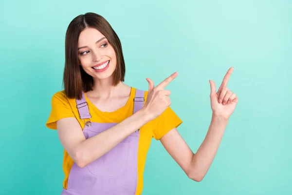 Foto van vrolijke jonge vrolijke positieve vrouw wijzen vinger kijken lege ruimte geïsoleerd op teal kleur achtergrond — Stockfoto