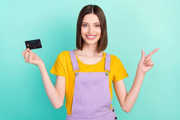 Fénykép a vidám fiatal nő mutatóujj üres hely tartsa hitelkártya elszigetelt pasztell rózsaszín háttér — Stock Fotó