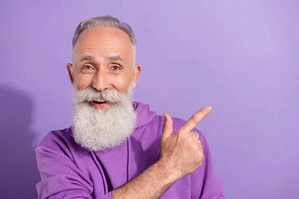 Portrait of attractive elderly retired trendy grey-haired man showing copy space advert isolated over purple violet color background — Stock Photo, Image