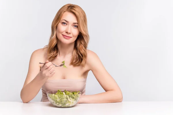 Портрет привабливої веселої здорової жінки в оголеному верхньому одязі, що їсть салат з веганськими овочами, ізольований на сірому пастельному кольоровому фоні — стокове фото