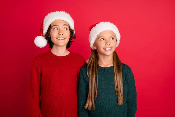 Портрет двух привлекательных веселых друзей в праздничной кепке фантазирует изолированы на ярко-красном фоне — стоковое фото
