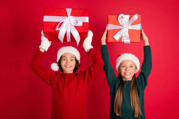 Portret van twee mooie verbaasd vrolijke vrienden vriendschap houden giftbox avond feestelijke dag geïsoleerd over helder rood kleur achtergrond — Stockfoto