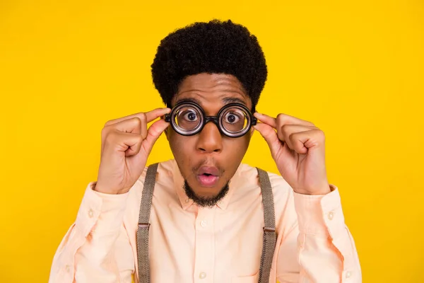 Foto retrato hombre en camisa con gafas que comprueban la vista sorprendido aislado de color amarillo brillante fondo — Foto de Stock