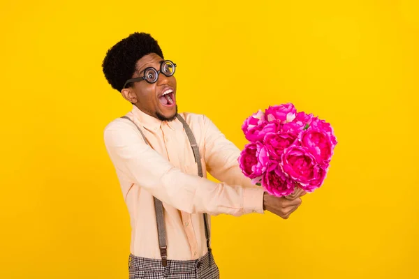 Foto retrato hombre en gafas dando peonys ramo emocionado en la fecha aislado color amarillo vivo fondo — Foto de Stock