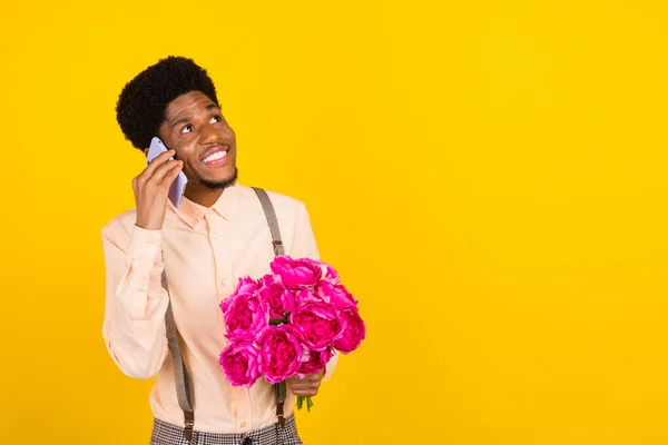 Foto di ragazzo sognante tenere bouquet telefono look spazio vuoto indossare bretelle camicia isolato colore giallo sfondo — Foto Stock
