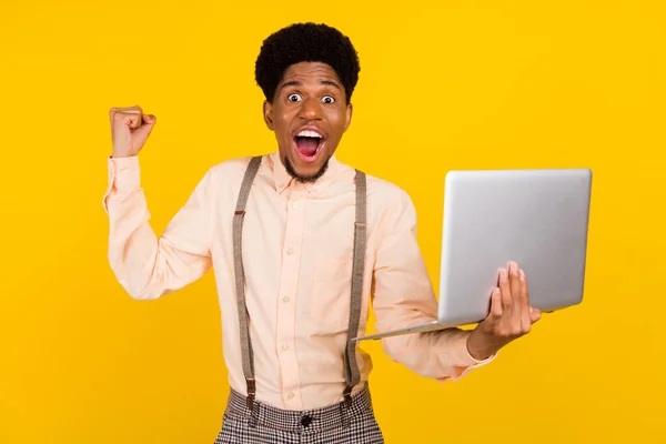 Foto portret man in shirt werken op laptop gebaren als winnaar geïsoleerde heldere gele kleur achtergrond — Stockfoto