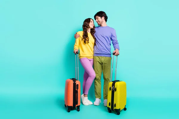 Celotělová fotografie mladého páru šťastný pozitivní úsměv objetí cestování muška tašky letiště izolované přes teal barva pozadí — Stock fotografie