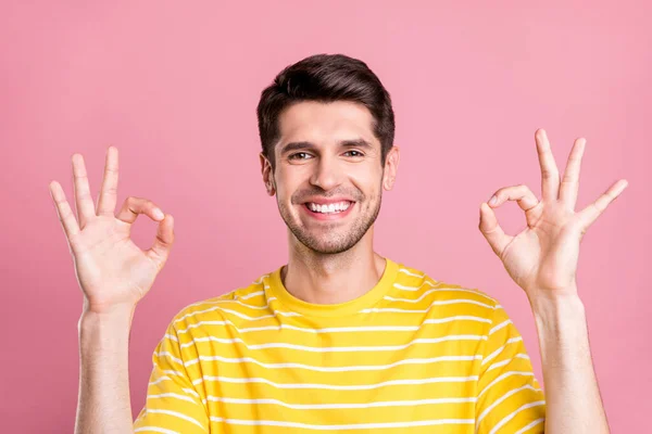 Zdjęcie śmieszne brunet młody człowiek pokazać okey znak nosić żółty t-shirt izolowane na różowy kolor tła — Zdjęcie stockowe
