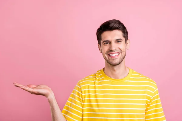 Portret van aantrekkelijke vrolijke man houden op palm kopieerruimte ad promo bieden geïsoleerd over roze pastel kleur achtergrond — Stockfoto