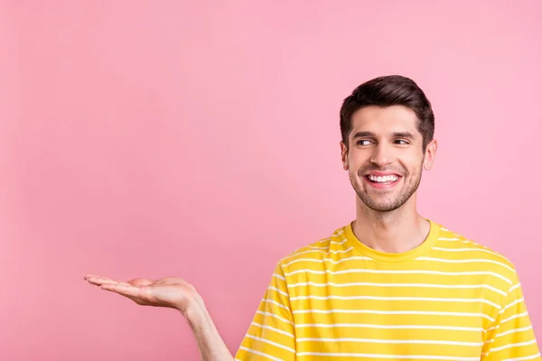 Retrato de chico alegre atractivo sosteniendo en copia de la palma vacío espacio en blanco anuncio oferta aislada sobre fondo de color pastel rosa — Foto de Stock