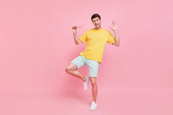 Pełna długość zdjęcie wesoły młody szczęśliwy człowiek taniec trzymać za rękę okulary lato izolowane na różowy kolor tła — Zdjęcie stockowe
