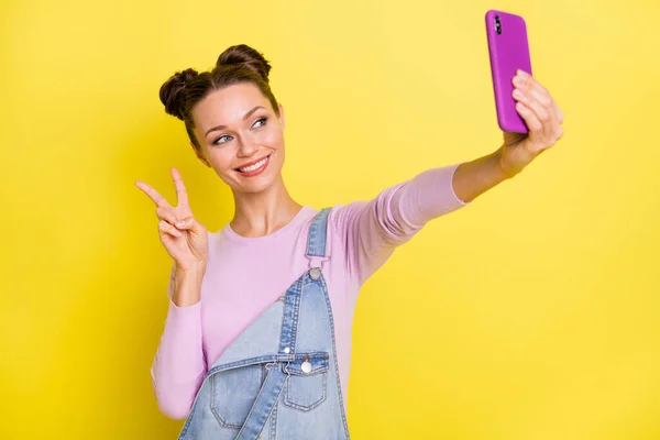 Foto de mujer encantadora brillante desgaste denim general viraje selfie dispositivo moderno que muestra v-signo aislado color amarillo fondo — Foto de Stock