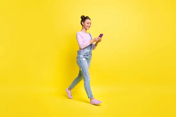 Volledige grootte profiel foto van optimistische mooie brunet dame ga kijken telefoon slijtage algemeen geïsoleerd op gele achtergrond — Stockfoto