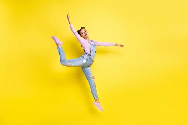 屈託のないダンサーの女性のジャンプの写真は、ピュレットは、ジーンズ全体の履物を着用黄色の背景 — ストック写真