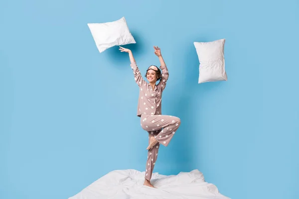Πλήρης φωτογραφία μεγέθους του νεαρού όμορφη χαρούμενη χαρούμενη κοπέλα με πιτζάμες με ιπτάμενα μαξιλάρια γύρω απομονωμένο σε μπλε φόντο χρώμα — Φωτογραφία Αρχείου
