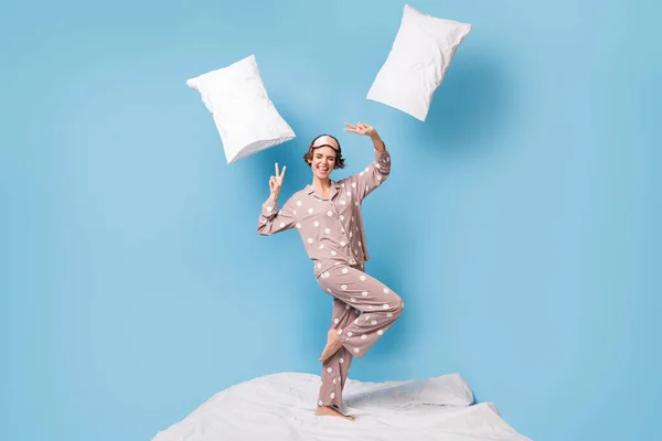 Foto em tamanho completo de jovem feliz louco engraçado sorrindo menina em pijama mostrando v-sinal isolado no fundo de cor azul — Fotografia de Stock