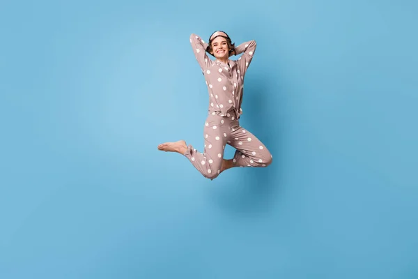 Полноразмерная фотография молодой счастливой, взволнованной, улыбающейся жизнерадостной девушки в пижаме, прыгающей на голубом цветном фоне — стоковое фото