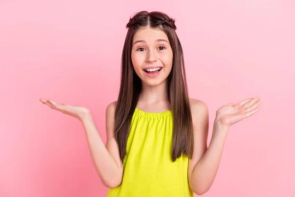 Foto de bonito animado pequena estudante vestida roupa amarela mostrando escalas espaço vazio sorrindo isolado cor de fundo rosa — Fotografia de Stock