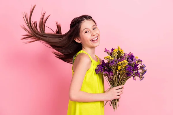 Fénykép csinos imádnivaló tizenéves iskolás lány viselni sárga ruhák mosolygós gazdaság virágok csokor elszigetelt rózsaszín szín háttér — Stock Fotó
