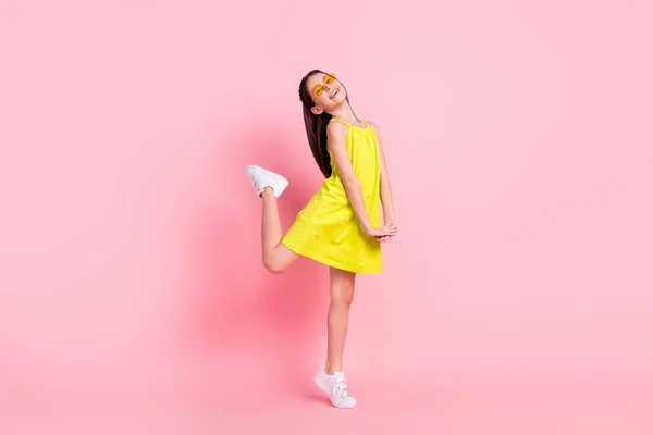 Фотографія повної довжини красивої школярки, одягнена в жовтий одяг темні окуляри, танцює усміхнений ізольований рожевий колір фону — стокове фото