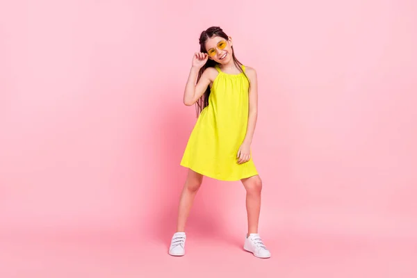 Фотографія солодкої смішної школярки, одягнена в жовтий одяг темні окуляри, танцює усміхнений ізольований рожевий колір фону — стокове фото